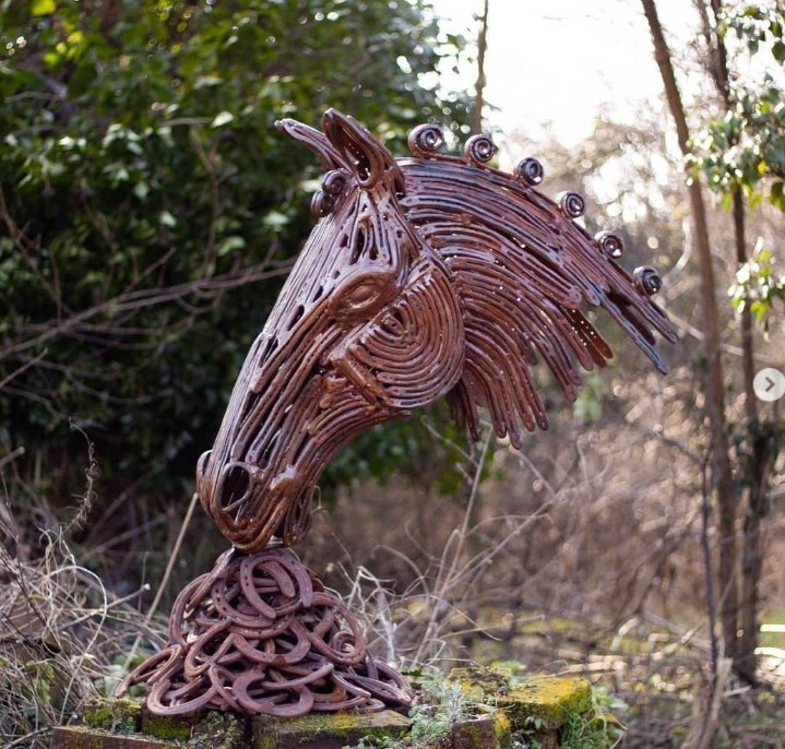 Metal horseshoe sculpture eating pile of hay