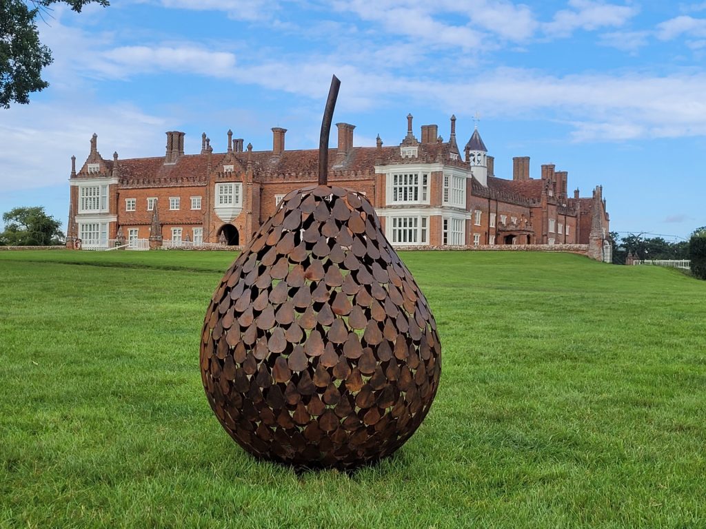 Metal pear sculpture in front of stately home