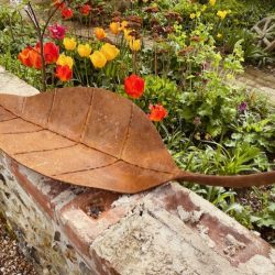 Metal leaf on wall with tulips in background