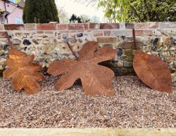 three leaf sculptures leaning on an old wall