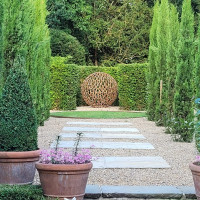 Sphere sculpture in landscaped garden surrounded by hedges