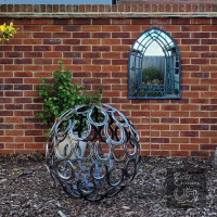Horseshoe sphere sculpture in modern garden with mirror
